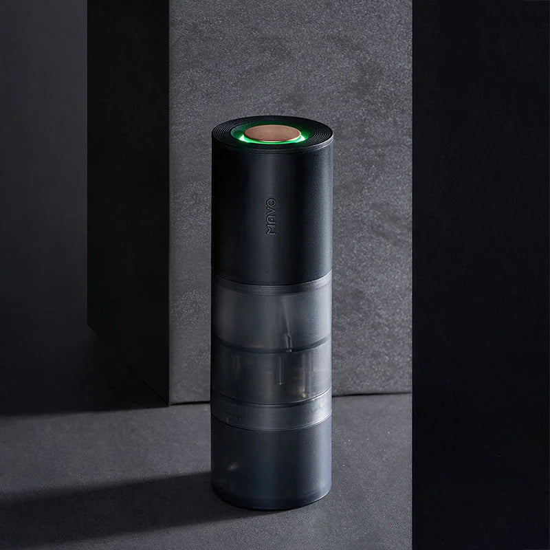 MAVO Aurora electric coffee grinder standing on dark stone with its green breathing light lit
