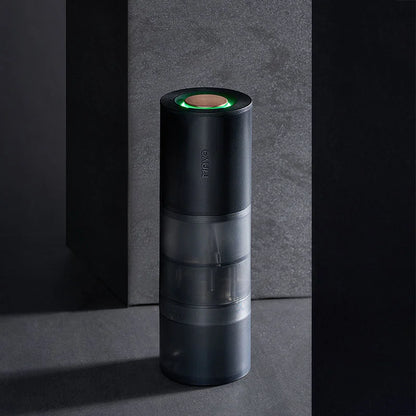 MAVO Aurora electric coffee grinder standing on dark stone with its green breathing light lit