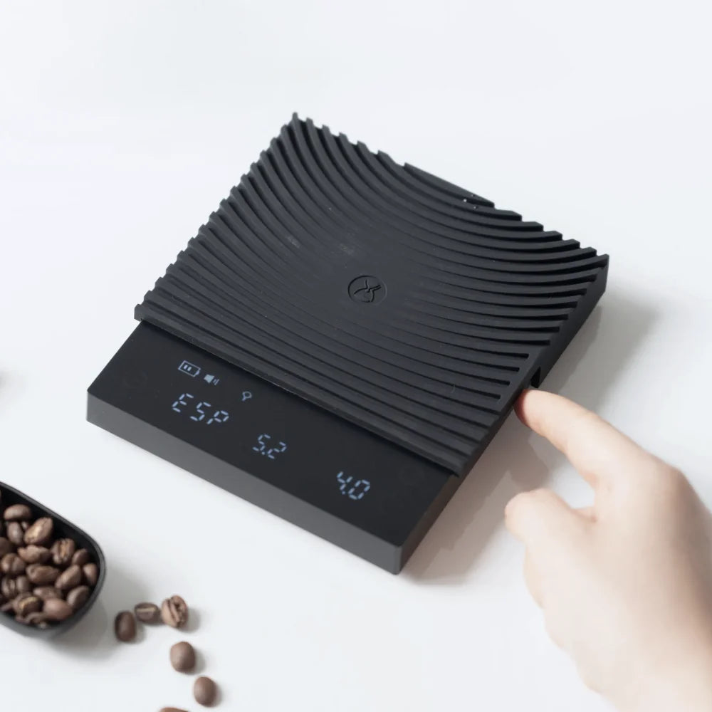 A finger moving the multifunction slider on the side of the black TIMEMORE Basic 3, the display reading ESP for espresso mode with weight and time
