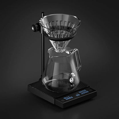 A glass dripper and carafe on the DUO in the dark with the scale's display glowing blue at the front