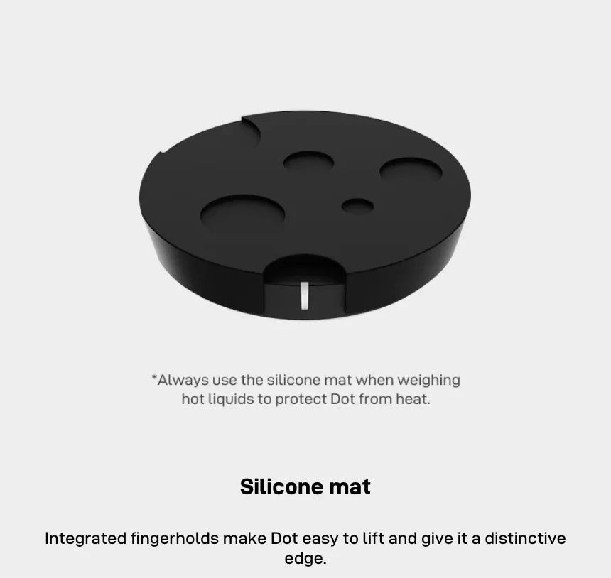 Silicone mat: a black mat with four round recesses and a finger notch that holds the Dot, with the note to always use the silicone mat when weighing hot liquids to protect the Dot from heat