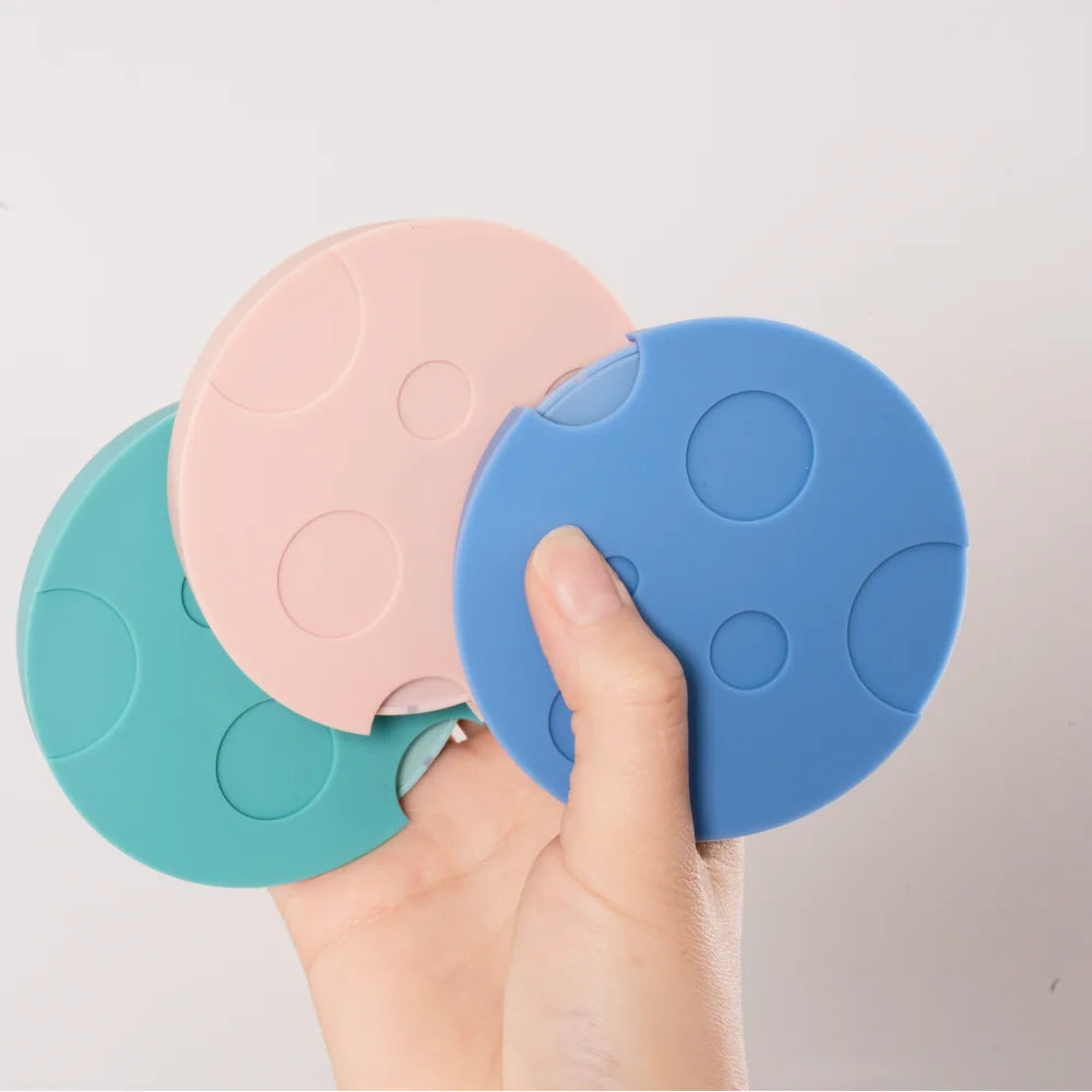 A hand holding a fan of pink, blue and teal TIMEMORE Dot silicone mats, each with a pattern of round craters