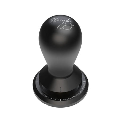 Black FLOW tamper seen from above at an angle, the teardrop handle engraved with Anthony Douglas's signature and a ring of engraved text around the base