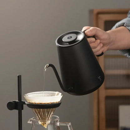 Pouring from the TIMEMORE Fish Pro X into a pour over dripper on a stand, hand on the cutaway handle