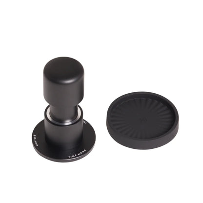 TIMEMORE Impulse Impact Tamper standing on its 58.4mm base beside its round ribbed silicone base on a white background