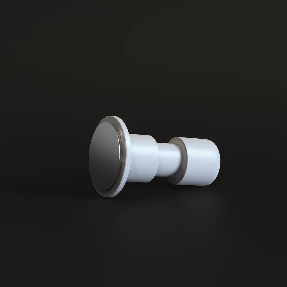 White Impulse Impact Tamper lying on its side on a dark surface with its flat 58.4mm base facing the camera