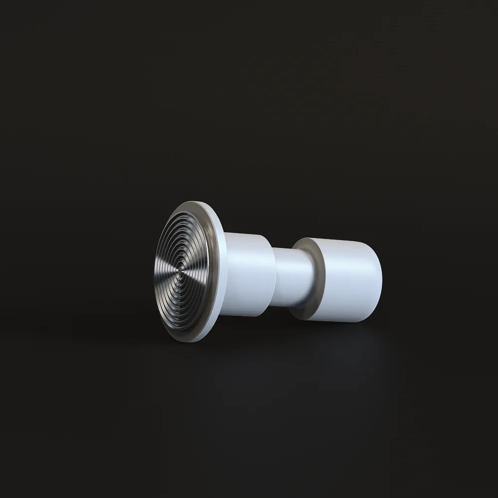 White Impulse Impact Tamper lying on its side on a dark surface with its concentric ripple 58.4mm base facing the camera
