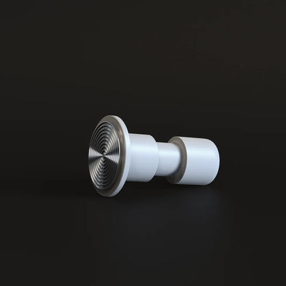 White Impulse Impact Tamper lying on its side on a dark surface with its concentric ripple 58.4mm base facing the camera
