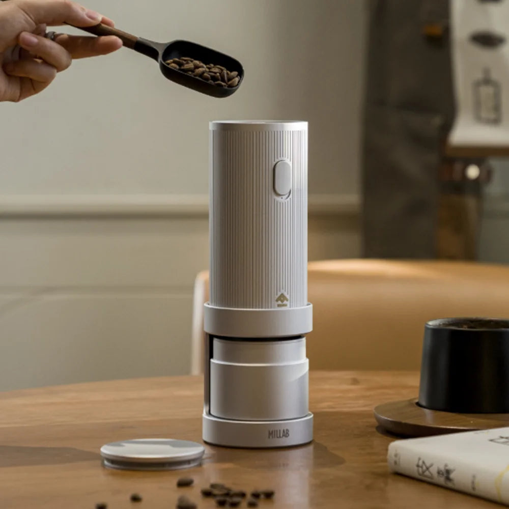 Beans being scooped into the TIMEMORE x MILLAB E01 on its stand on a wooden café table