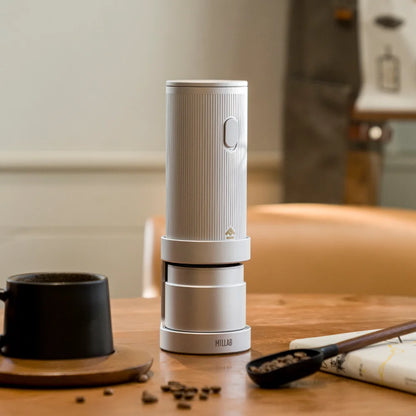 TIMEMORE x MILLAB E01 on its stand on a wooden table with a black mug, coffee scoop and beans