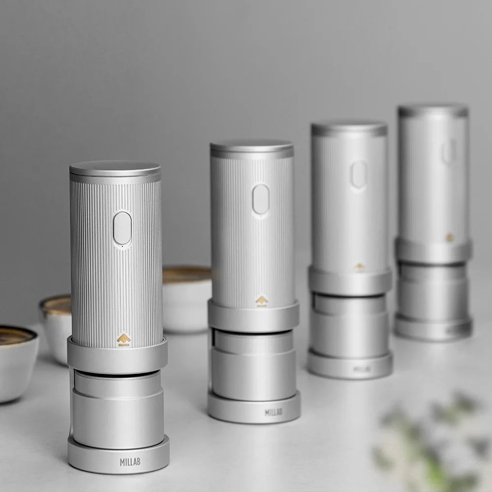 Four TIMEMORE x MILLAB E01 grinders lined up on a coffee cupping table