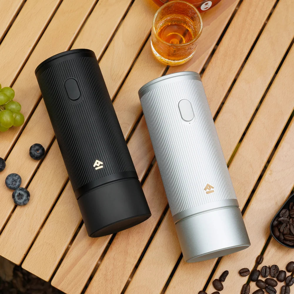 Two TIMEMORE x MILLAB E01 grinders, one black and one silver, lying on a slatted wooden camping table with fruit and coffee beans