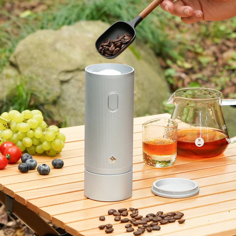 TIMEMORE x MILLAB E01 on its stand on an outdoor camping table as beans are scooped into the top-loading bean chamber
