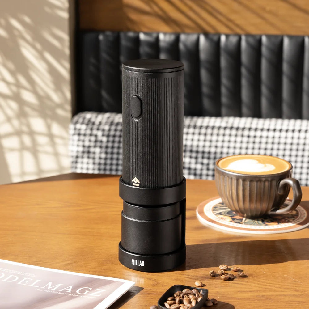 TIMEMORE x MILLAB E01 on its stand on a café table beside a latte and a scoop of coffee beans