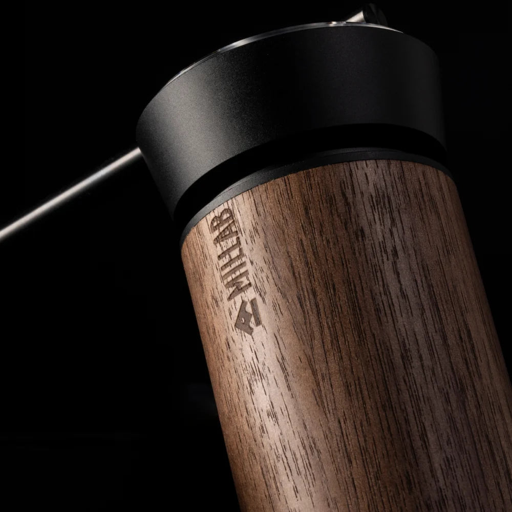Low-light close-up of the M01's walnut grip with the engraved MILLAB logo under the black top collar