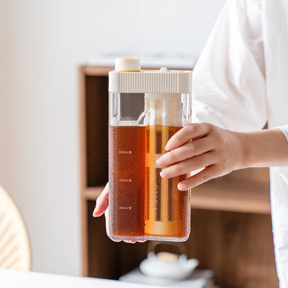 Hand holding the MAVO Crysbrick Cold Brewer filled with cold brew coffee, 200-800ml scale visible